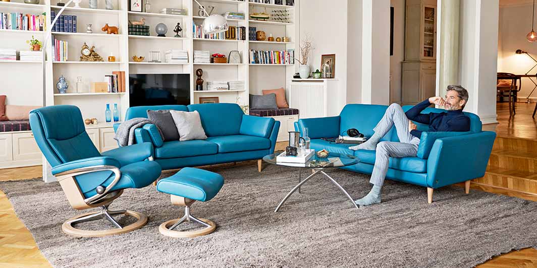 Blauer Relaxsessel und Sofakombination Mann entspannt auf Stressless Sofa