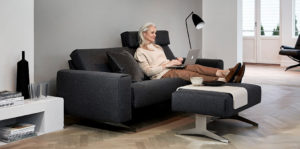 Frau auf Stressless Sofa mit Laptop, graues Sofa mit Fußbank
